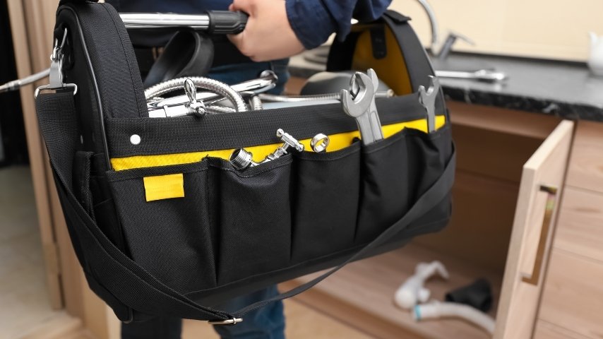 Plumber carrying a tool bag up to the front door of a terraced house