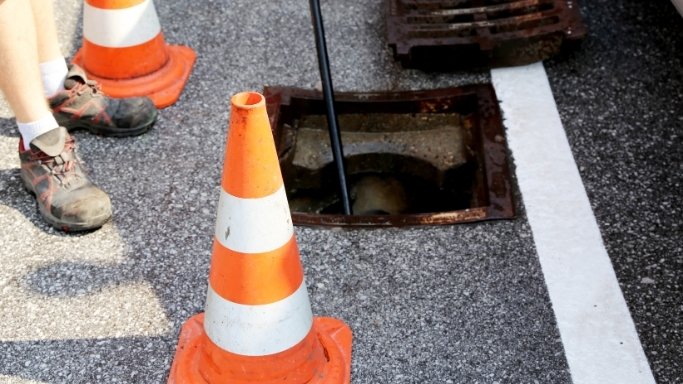 Drain rods being fed into an outside gully in a terraced back yard